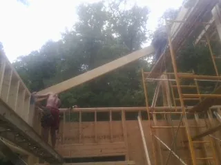 Carpenter raising a rafter beam on a new second story frame in Rosendale