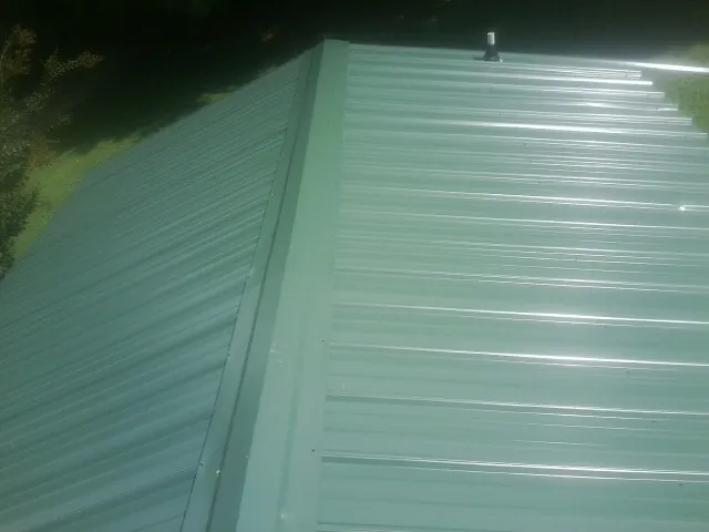 New green metal panels meeting at the ridge of a roof — Flat Roof Repair work by our crew in Rosendale