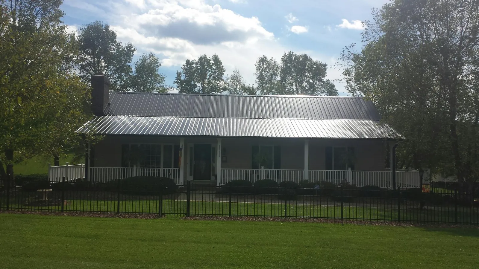 Gray metal roof on a brick ranch with a full width front porch — Gutter Guard Installation work by our crew in Rosendale