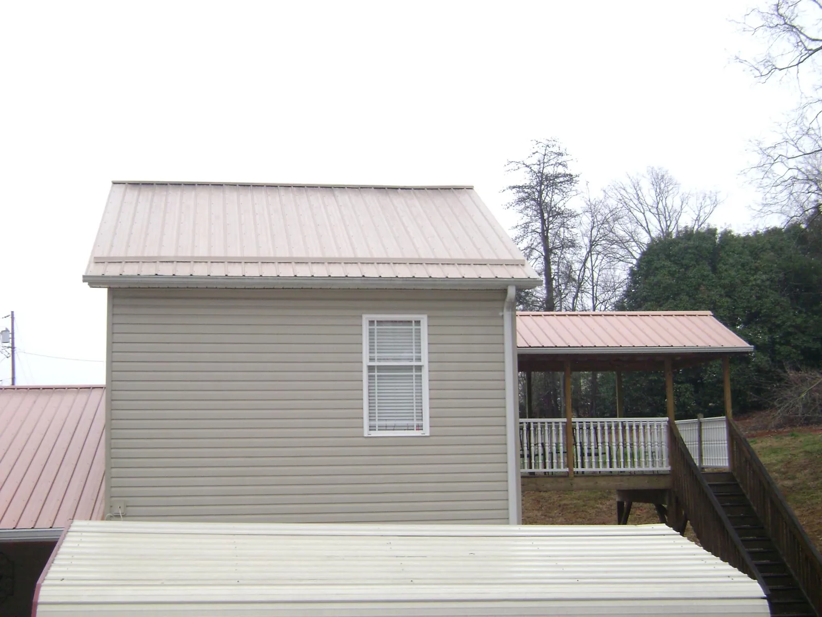 Tan metal roofs on a two story addition and attached porch, from a Roof Replacement job in Rosendale