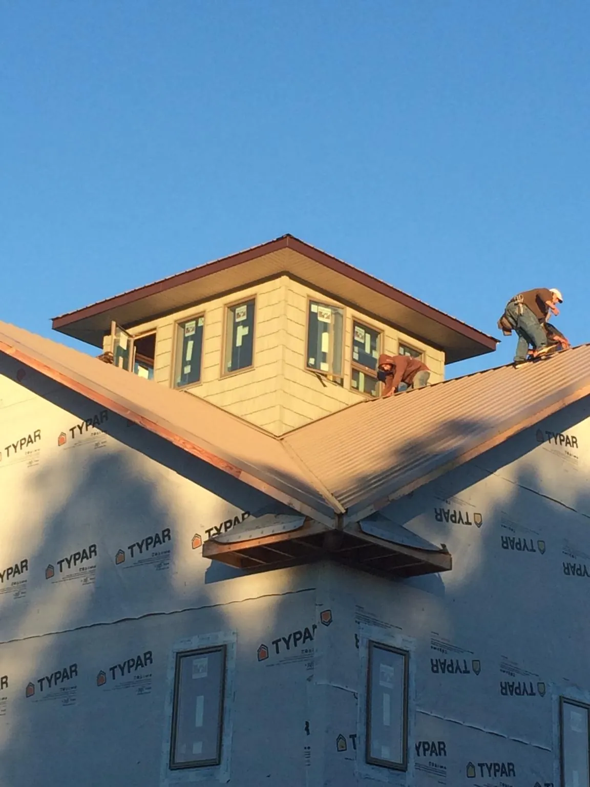 Roofers working around a rooftop cupola on a new metal roof at sunset — Roof Waterproofing in Rosendale by Roofing Brothers